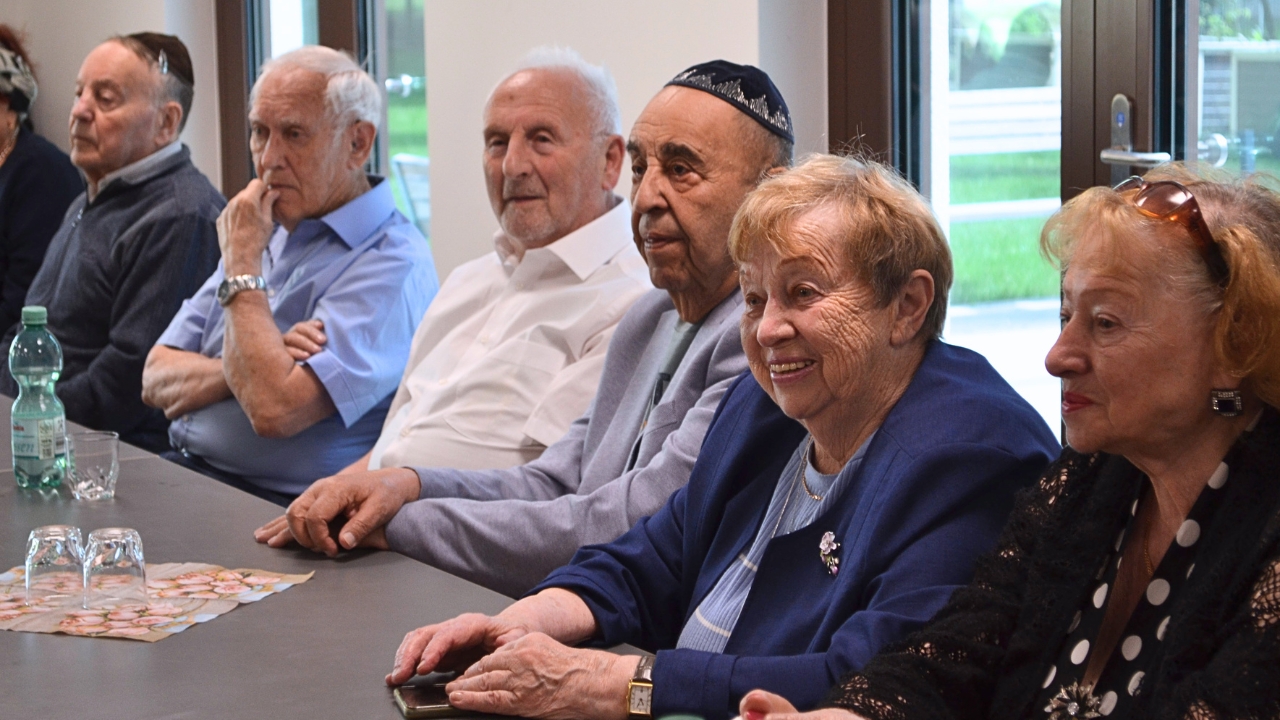 Eine Gruppe Seniorinnen und Senioren lächeln an einem Tisch