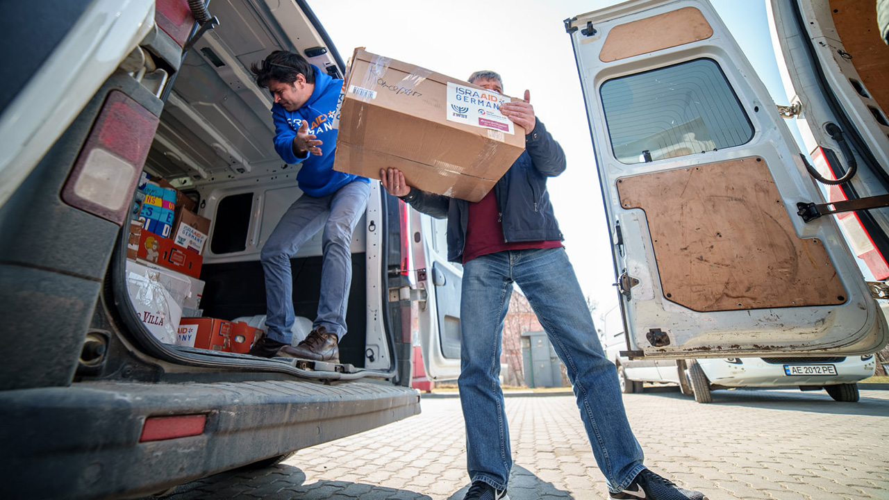 Zwei Männer verladen Kiste in Transporter