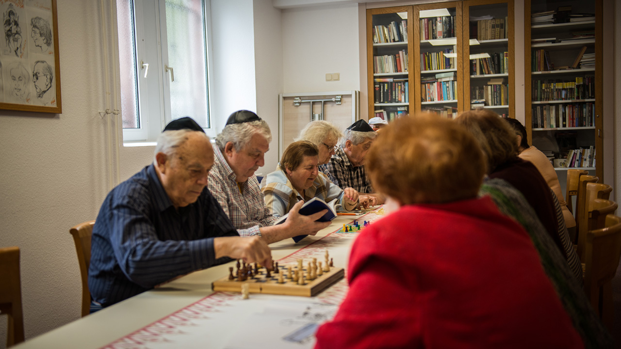 eine Gruppe von Senioren sitzt am Tisch und einige spielen Schach