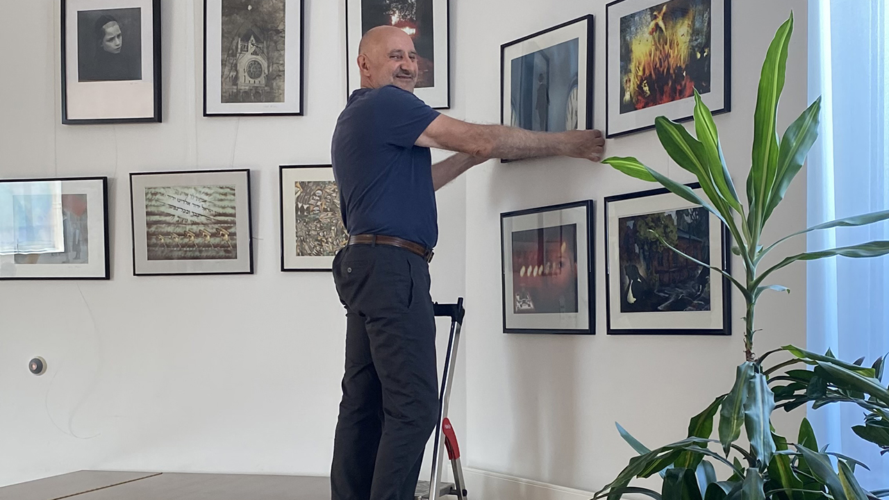 Mann auf der Leiter hängt Bilder auf