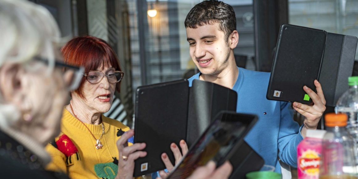 Junger Mann erklärt einer älteren Frau wie man ein Tablet benutzt