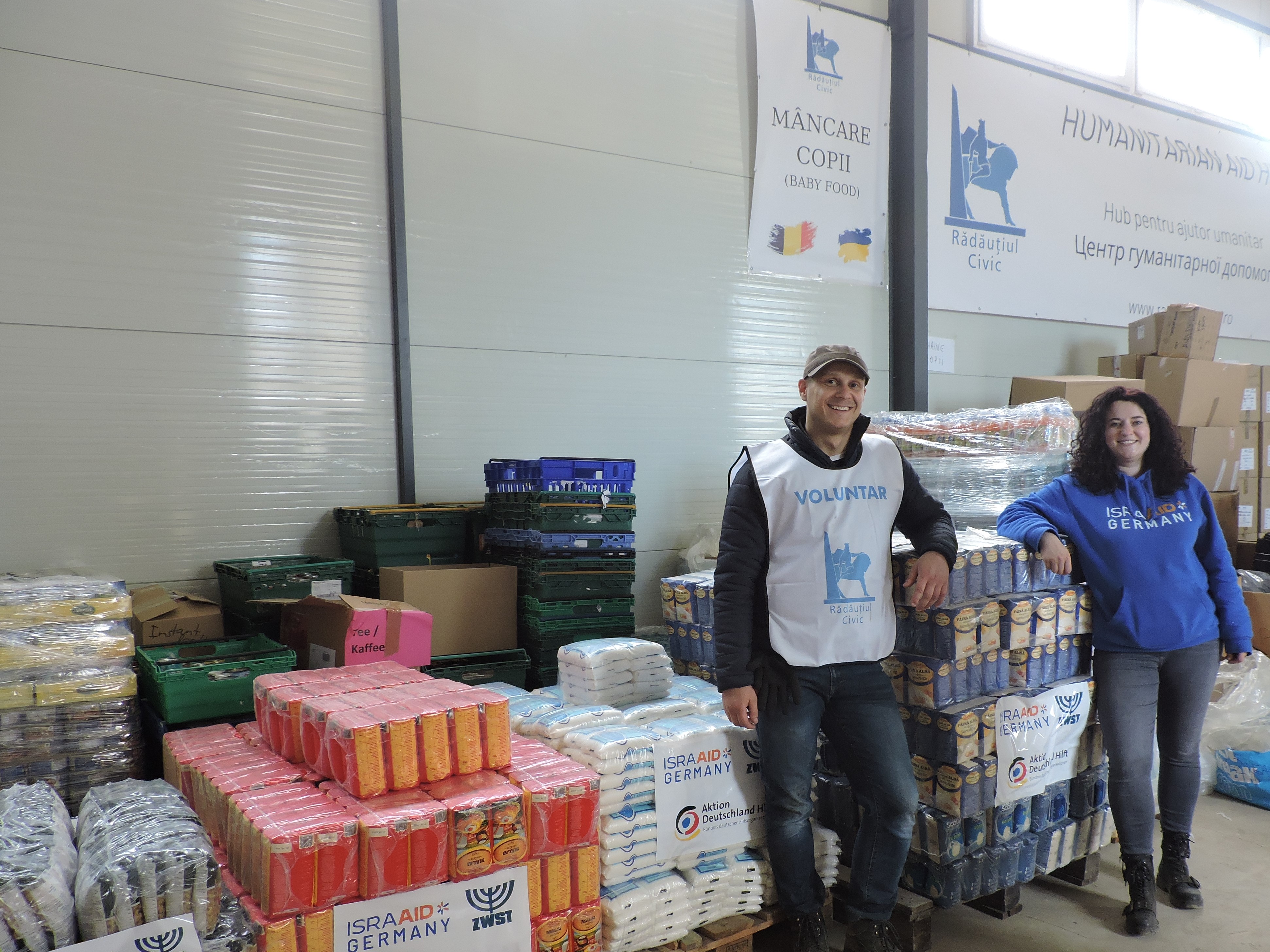 Darya von IsraAID Germany und Andrei von Rădăuțiul Civic beim Sortieren und Ausladen von Lebensmitteln und Medikamenten für die nächsten Hilfslieferungen. 