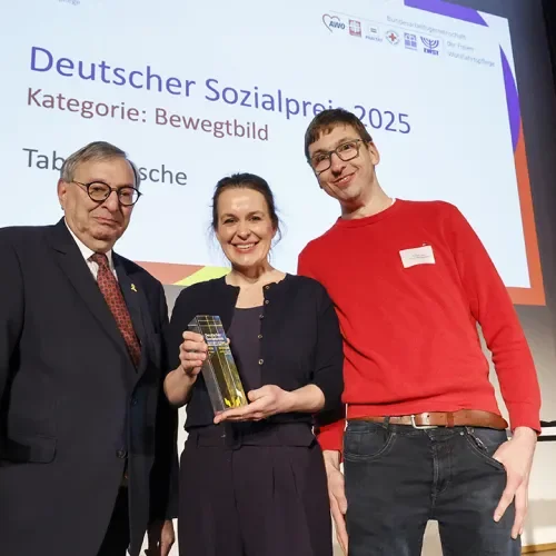 Drei Menschen lächeln in die Kamera