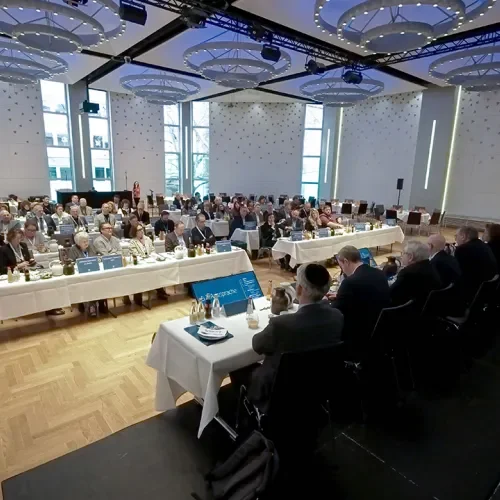 Blick in einen Tagungsraum mit vielen Teilnehmenern und Podium