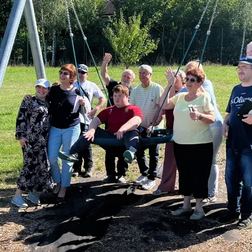 Eine kleine Gruppe von Menschen unterschiedlichen Alters mit einer Schaukel