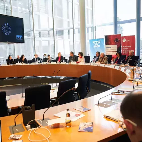 Menschen sitzen gemeinsam an großem rundem Tisch