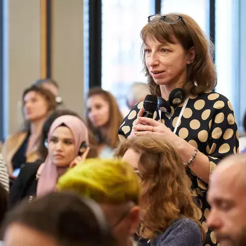 Eine Frau in einem Publikum spricht