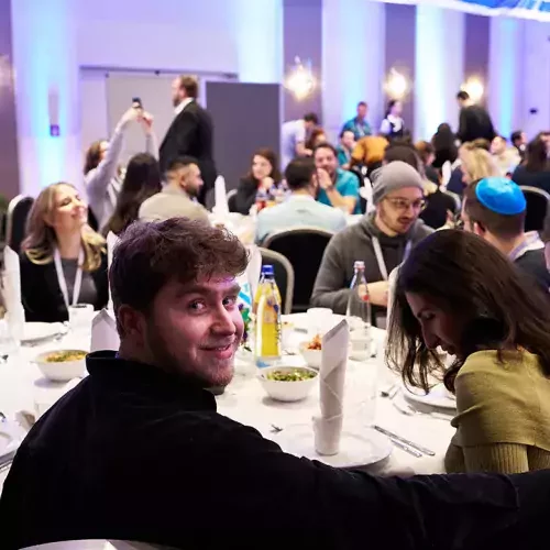 Junge Menschen sitzen an einem großem Essenstisch