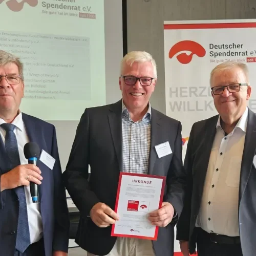 Drei Männer halten ein Spendenzertifikat