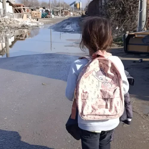 Ein Mädchen mit Rucksack läuft eine Straße entlang