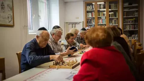eine Gruppe von Senioren sitzt am Tisch und einige spielen Schach