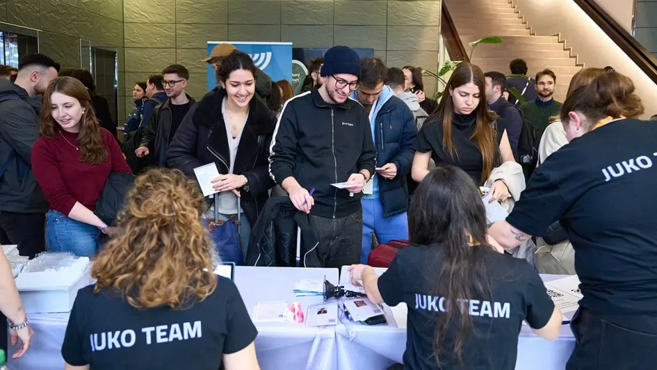 Junge Menschen an einem Checkin Tisch erhalten Teilnehmendenbadges