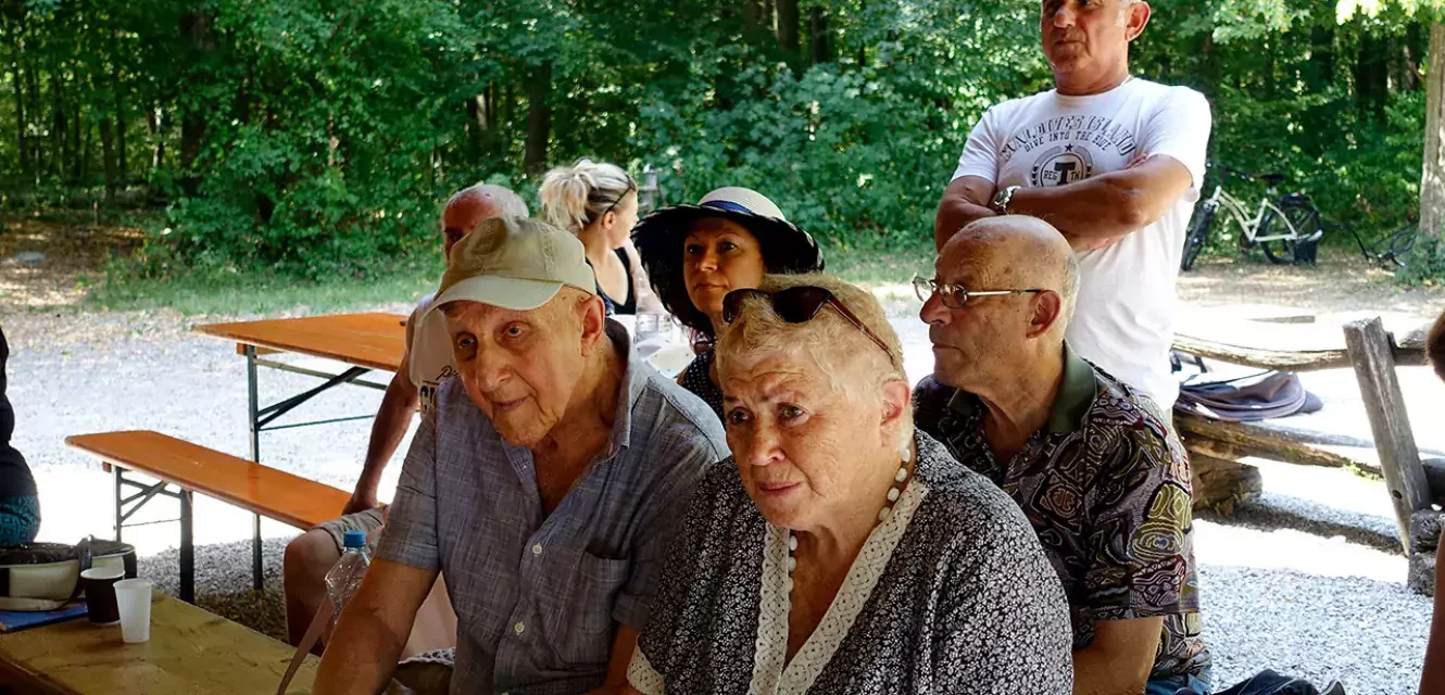 Eine Gruppe von Senioren und Seniorinnen sitzt auf einer Bank