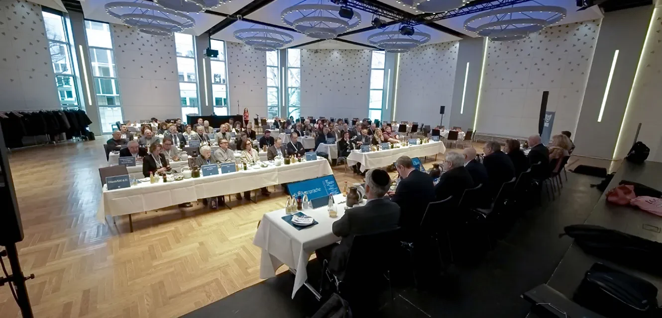 Blick in einen Tagungsraum mit vielen Teilnehmenern und Podium