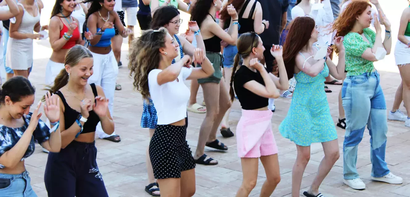 große Gruppe von Jugendlichen und Kindern tanzt im Freien