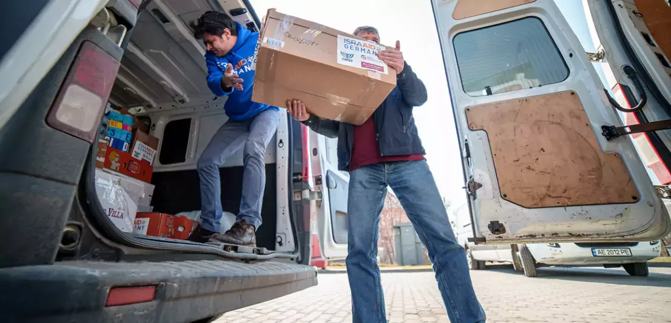 Zwei Männer verladen Kiste in Transporter