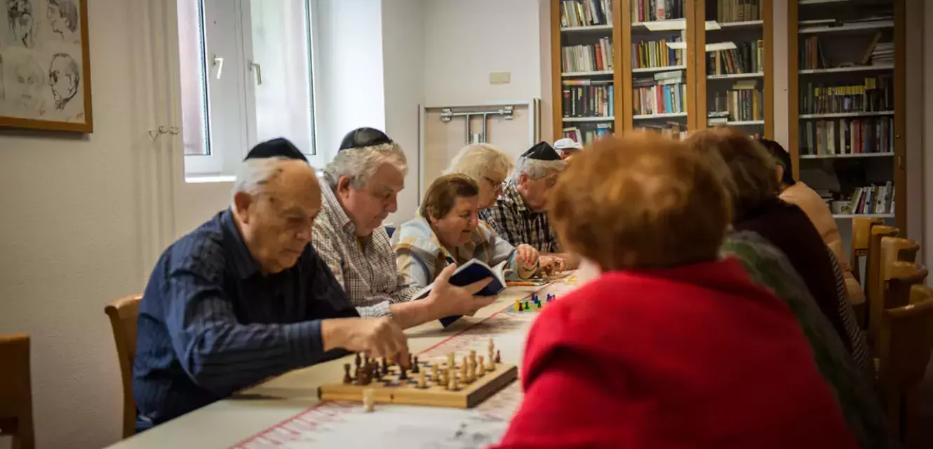 eine Gruppe von Senioren sitzt am Tisch und einige spielen Schach