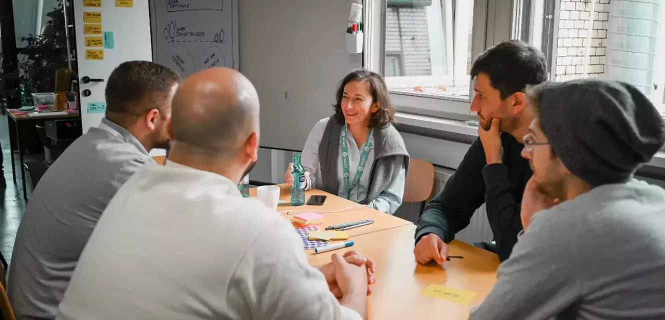 Gruppe von Menschen diskutiert an einem Tisch