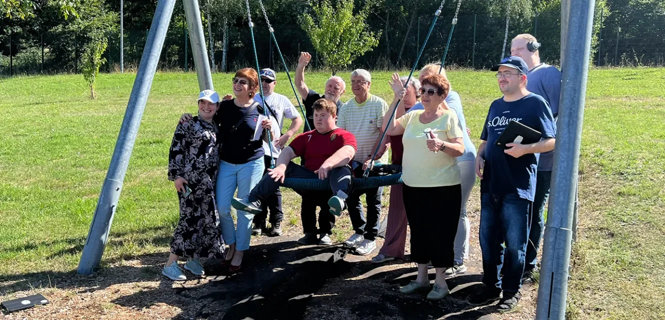 Eine kleine Gruppe von Menschen unterschiedlichen Alters mit einer Schaukel 