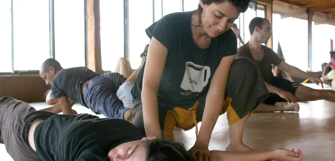 Eine Frau legt einer anderen Frau ihre Hand auf ihr Ohr in einer Meditation