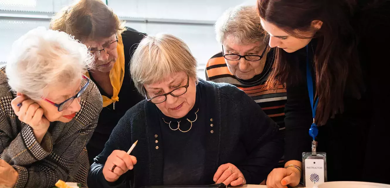 Gruppe von Senioren und Seniorinnen arbeitet an einem Tablet