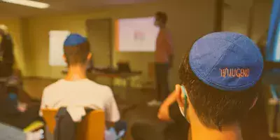 Ein Kopf eines Jugendlichen mit einer beschrifteten Kippa