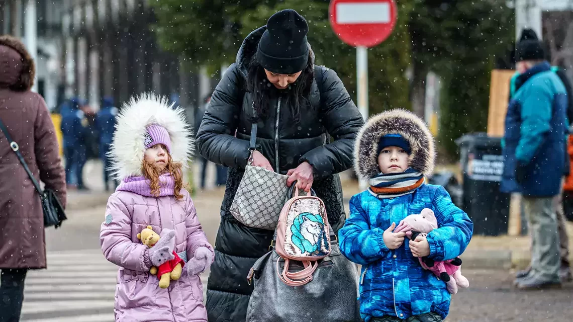Eine Mutter und ihre zwei Kinder laufen über eine Straße