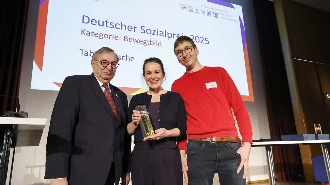 Drei Menschen lächeln in die Kamera