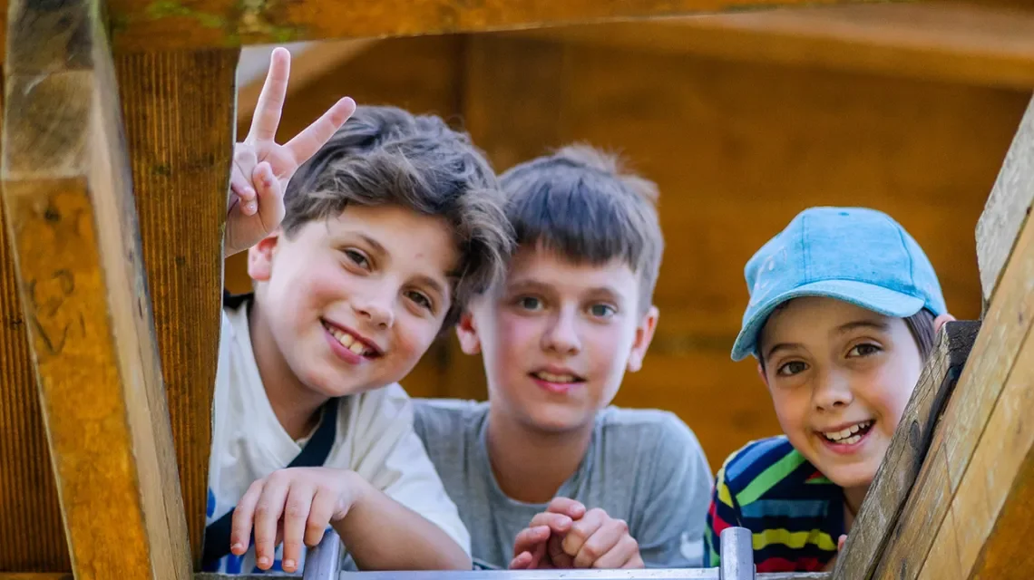 Drei Jungs lächeln von oben in die Kamera