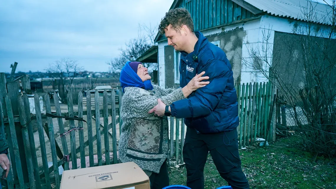 Junger Mann bringt alter Frau Hilfspakete