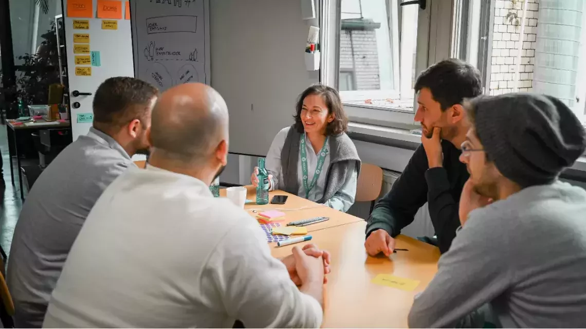 Gruppe von Menschen diskutiert an einem Tisch