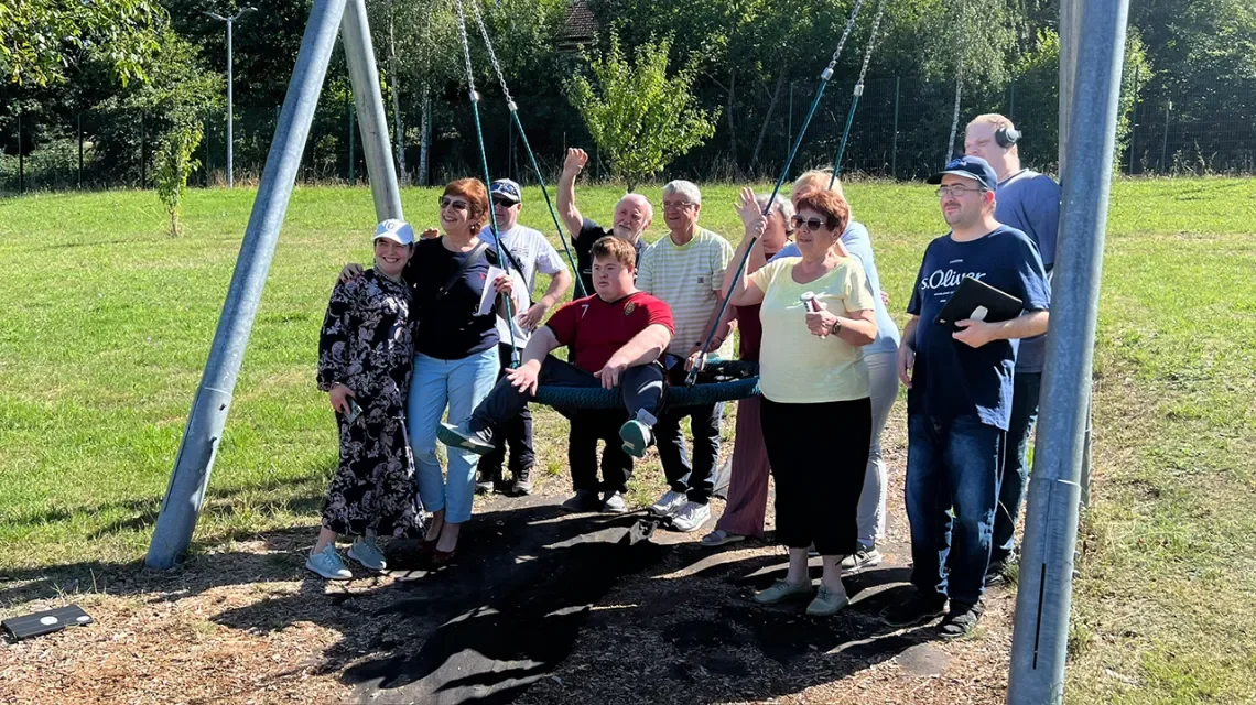 Eine kleine Gruppe von Menschen unterschiedlichen Alters mit einer Schaukel