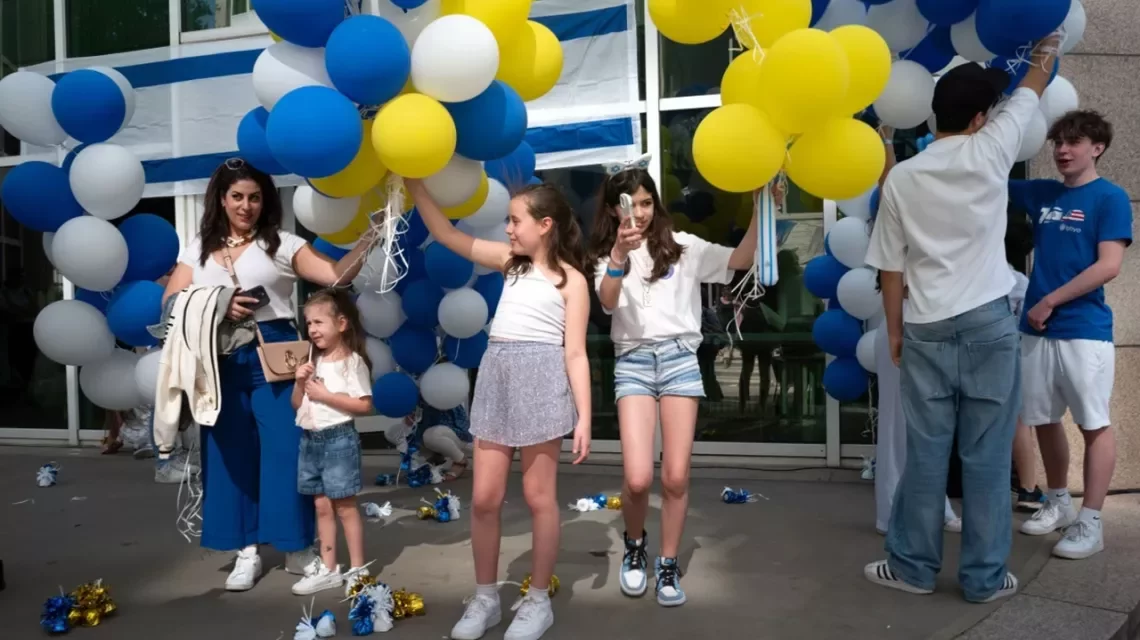 Kinder tanzen mit weißen, blauen und gelben Ballons
