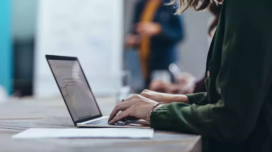 Frau tippt an einem Laptop