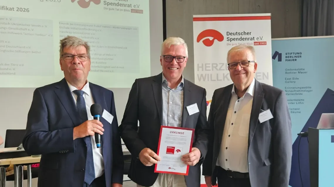Drei Männer halten ein Spendenzertifikat